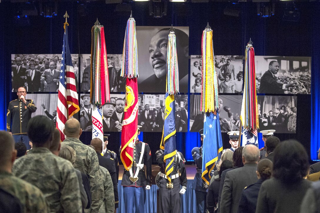 Audience members stand for a color guard ceremony.