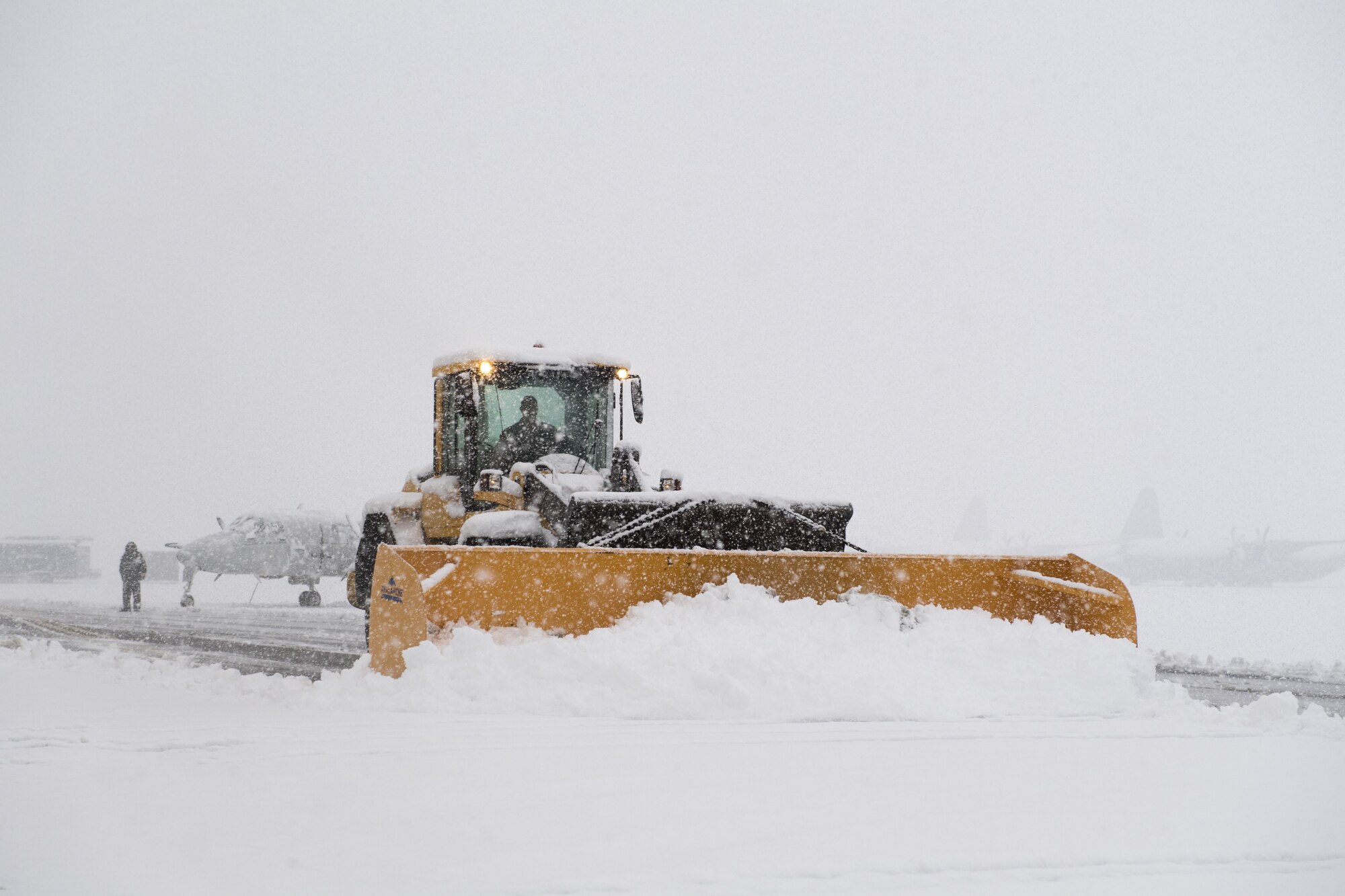 A 374th Civil Engineer Squadron Airman uses a front end loader with a snowplow attachment to remove snow from the flightline, Jan. 22, 2018, at Yokota Air Base, Japan.