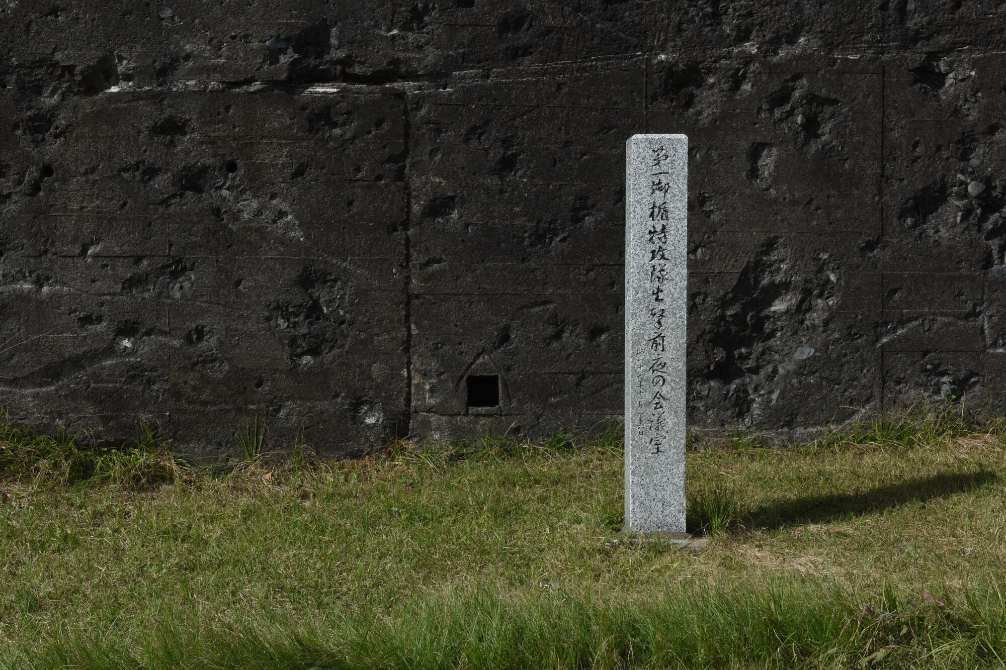 A memorial marker placed in front of the remnants of an embattled bunker on the island of Iwo To, Japan.