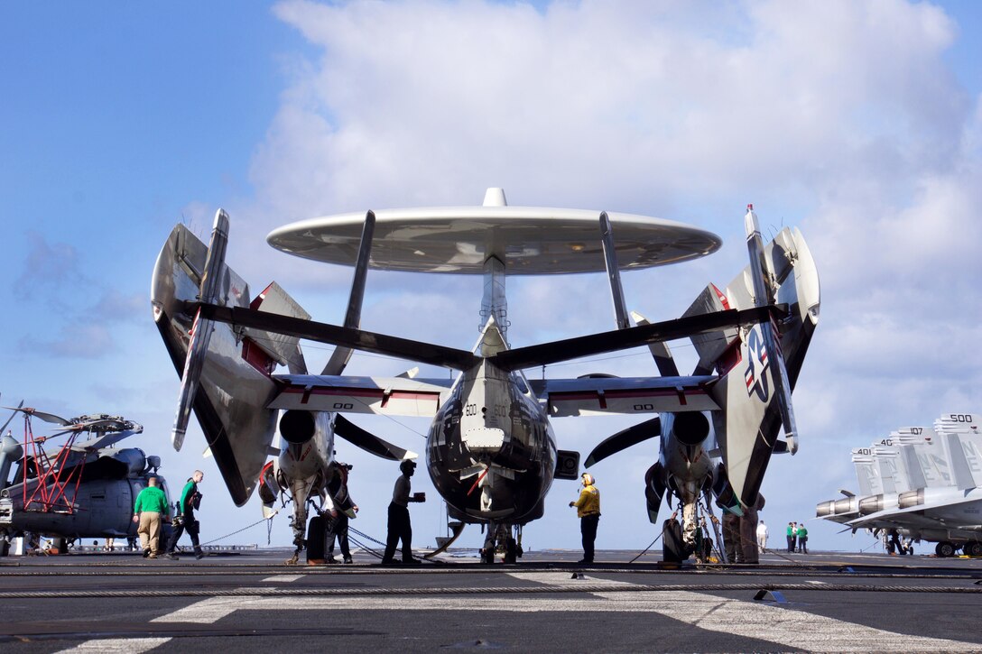 Sailors perform pre-flight checks on an E-2C Hawkeye.