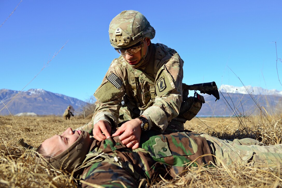 A soldier provides medical aid to an enemy combatant role-player.