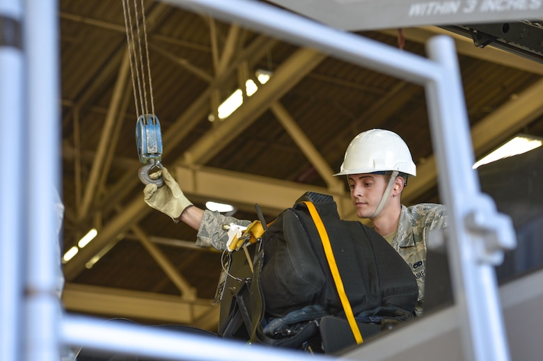 Airman 1st Class Matthew Romano, 56th Component Maintenance Squadron egress systems technician, guides a support hook to connect to an F-35A Lightning II ejection seat at Luke Air Force Base, Ariz., Jan. 11, 2018. Since October 2015, pilots weighing less than 136 pounds have been restricted from flying the F-35 due to concerns of possible neck injuries resulting if pilots engaged in ejection seat procedures. In May 2017, three modifications were implemented to the F-35A ejection system allowing Air Force leaders to remove the weight limit restriction on pilots. (U.S. Air Force photo/Airman 1st Class Caleb Worpel)