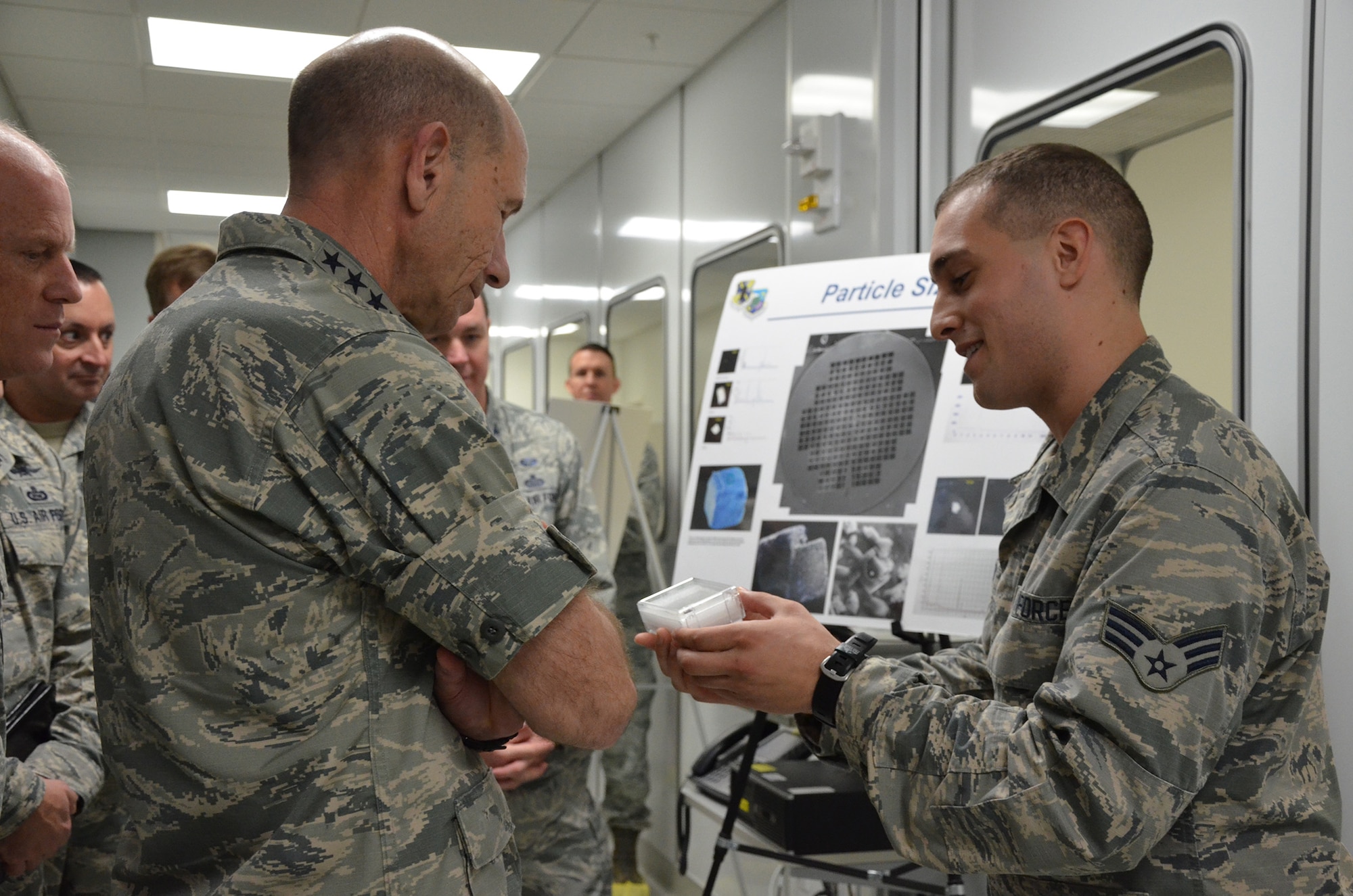 Senior Airman Dylan B. Melone (right), a clean room technician with the Air Force Technical Applications Center, shows Gen. Mike Holmes, commander of Air Combat Command, a transmission electron microscope grid he uses to accomplish AFTAC's trace particle analysis mission.  Holmes visited the nuclear treaty monitoring center, Patrick AFB, Fla., Jan. 24, 2018.  (U.S. Air Force photo by Susan A. Romano)