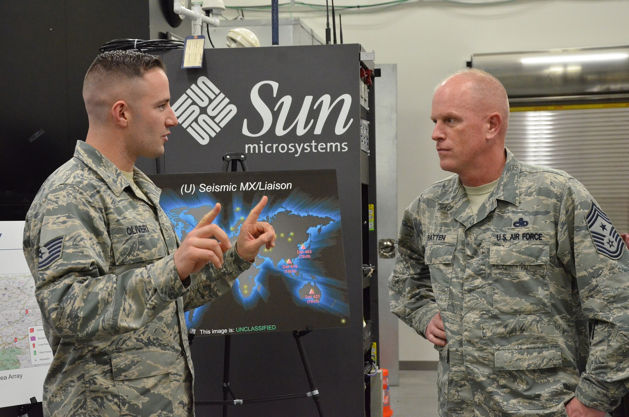 Tech. Sgt. Peter J. Oliveri (left), noncommissioned officer in charge of seismic field maintenance for the Air Force Technical Applications Center, Patrick AFB, Fla., discusses seismic operations with Chief Master Sgt. Frank Batten, command chief of Air Combat Command, during the chief's visit to the nuclear treaty monitoring center Jan. 24, 2018. Oliveri was one of many AFTAC Airmen who briefed Batten on the center's global mission.  (U.S. Air Force photo by Susan A. Romano)