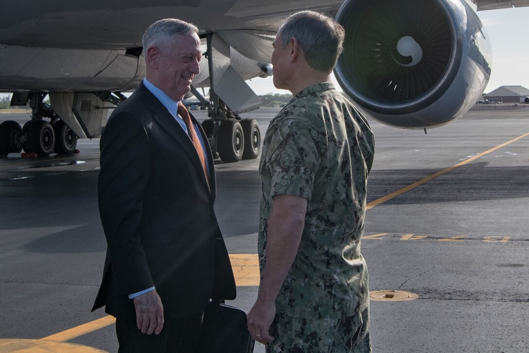 Defense Secretary James N. Mattis is greeted by a Navy commander on a runway.