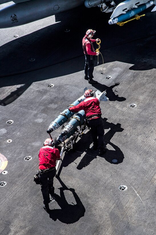 Sailors move ordnance across the flight deck of the Nimitz-class aircraft carrier USS Carl Vinson.