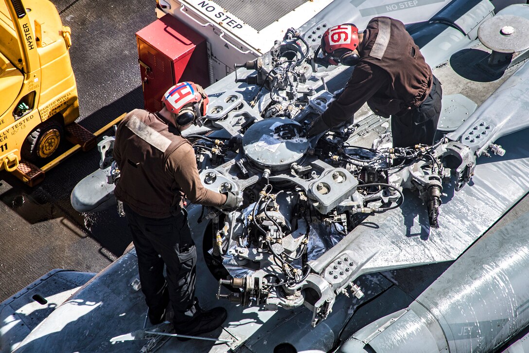 Sailors clean an MH-60S Sea Hawk helicopter.