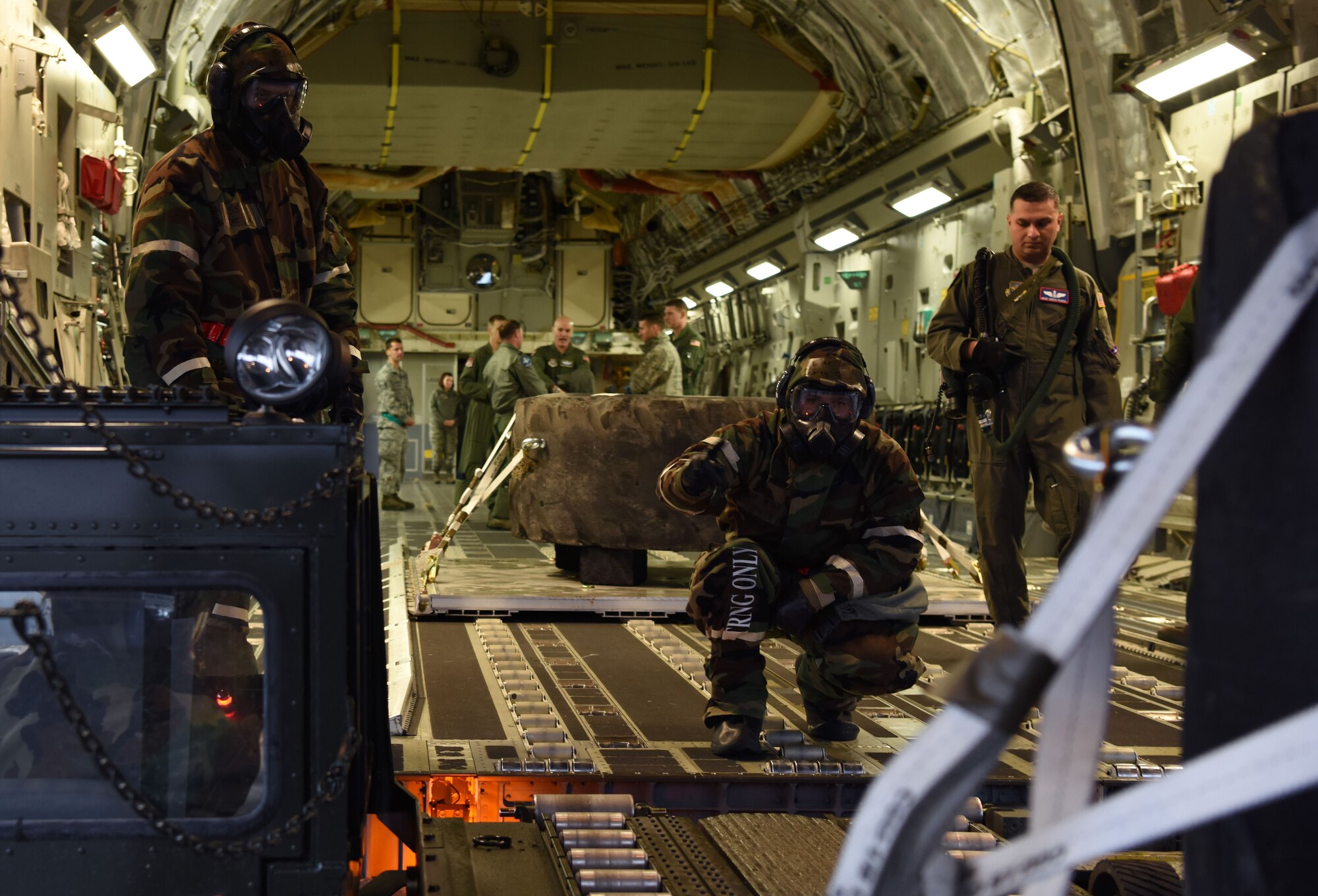 Airmen assigned to 62nd Airlift Wing and 627th Air Base Group load a C-17 Globemaster III during Exercise Winterhook at Joint Base Lewis-McChord, Wash., Jan. 25, 2018. During the exercise, Team McChord Airmen were tested and evaluated on their ability to properly wear mission oriented protective posture gear, perform their day-to-day duties and administer self-aid and buddy care during a simulated chemical threat. (U.S. Air Force photo by Senior Airman Tryphena Mayhugh)