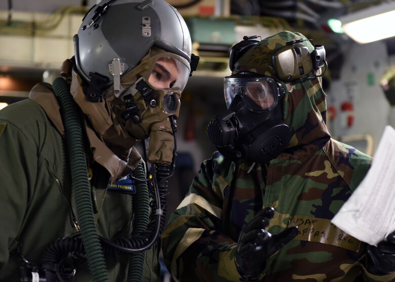 Tech. Sgt. Ryan Pappas, 62nd Aerial Port Squadron air transportation, discusses load plans with Senior Airman Darius Freeman, 7th Airlift Squadron loadmaster, prior to loading cargo on a C-17 Globemaster III during Exercise Winterhook, Jan. 25, 2018 on the McChord Field flightline at Joint Base Lewis-McChord. Throughout the exercise, Airmen demonstrated proficiency not only in utilizing MOPP gear effectively at all five levels, but in carrying out job-related tasks while wearing the gear. (U.S. Air Force photo by Staff Sgt. Whitney Taylor)