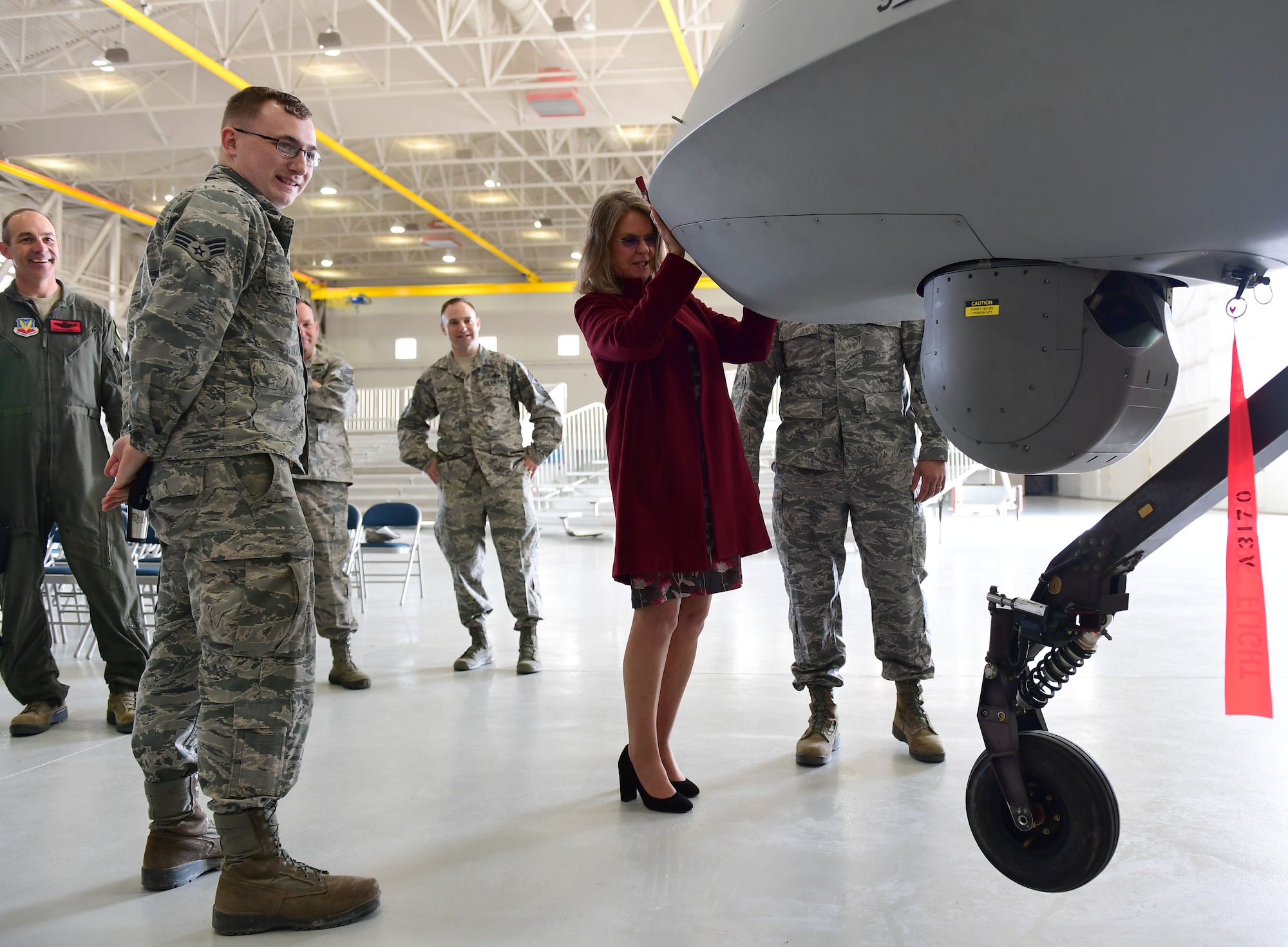 Ms. Jonna Doolittle Hoppes, executive director of the Doolittle Foundation and granddaughter of Gen. James “Jimmy” Doolittle, lifts the nose of an MQ-1 Predator off the ground Jan. 18, 2018, at Creech Air Force Base, Nev. Ms. Doolittle Hoppes toured the base with retired Lt. Gen. Christopher Miller, president of the Air Force Historical Foundation, before presenting the General James H. “Jimmy” Doolittle award to the 432nd Wing/432nd Air Expeditionary Wing. (U.S. Air Force photo/Senior Airman Christian Clausen)