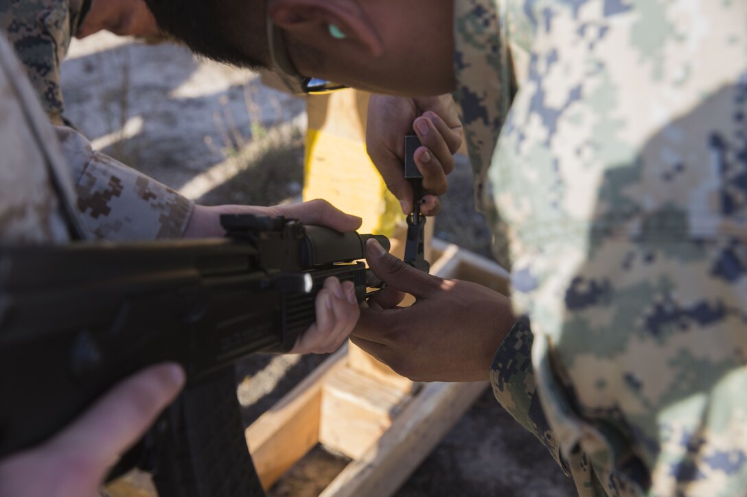 A tactics instructor with the I Marine Expeditionary Force Advisor Training Branch adjusts the sights on an AK-47 assault rifle as part of a foreign weapons demonstration for Marines with Task Force Al-Taqaddum 18.
