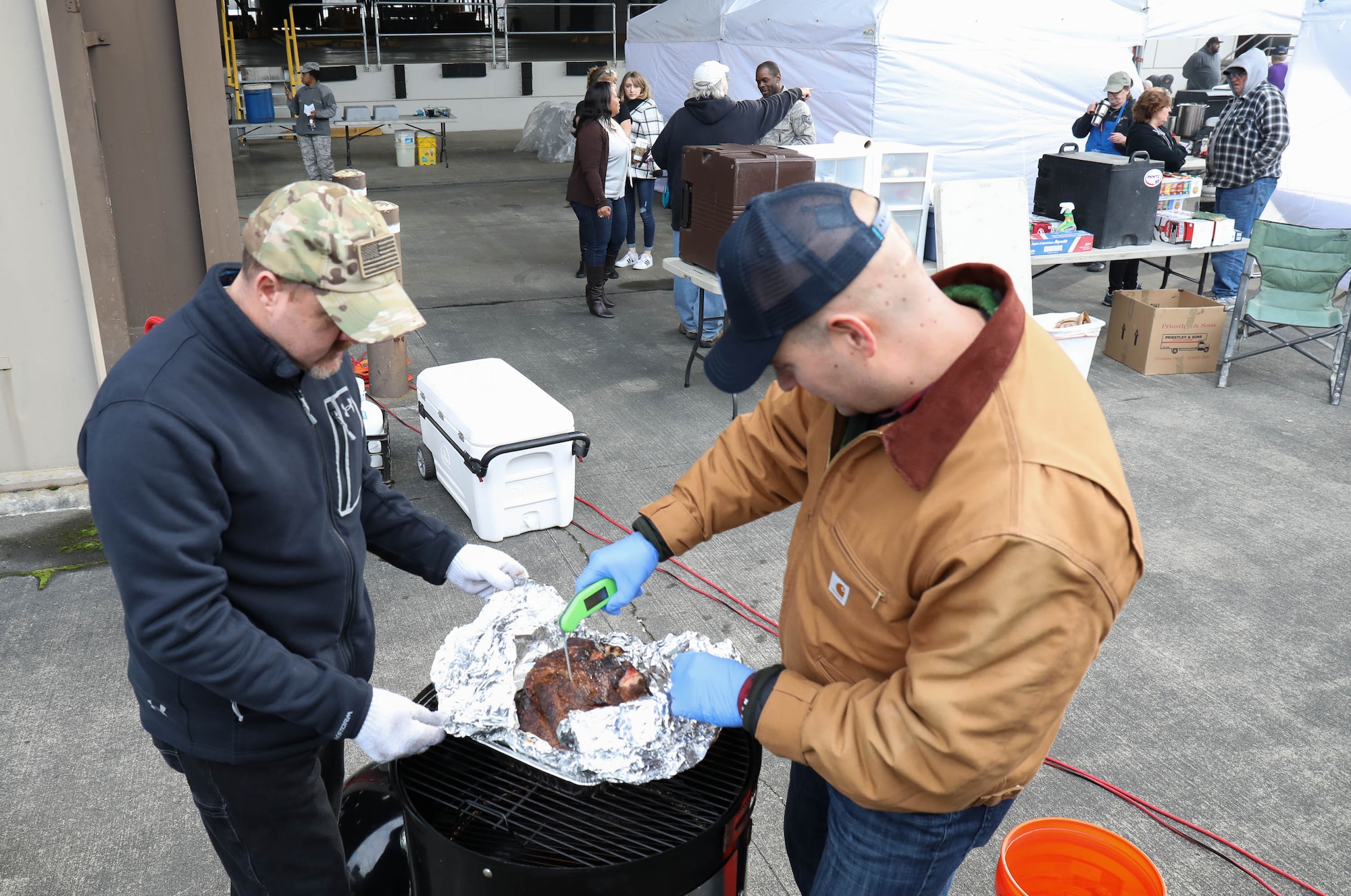 Scott Plocar and Tech. Sgt. John Hillenbrand of the 446th Airlift Wing check the temperature of a pork butt being cooked for a Diversity Day celebration Jan. 19, 2018, on Joint Base Lewis-McChord. Barbecue prepared by Washington State pitmasters, paired with members of both the 62nd and 446th Airlift Wings, was served to JBLM personnel free of charge.