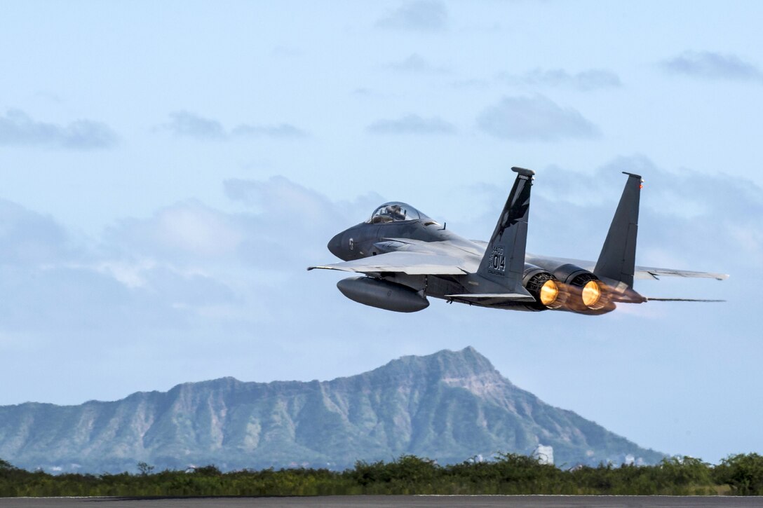 A jet flies toward a section of Diamond Head's ridgeline in the distance.