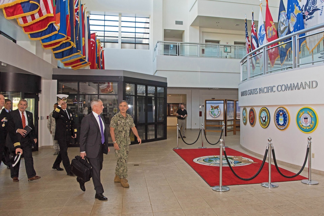 Defense Secretary James N. Mattis walks with the U.S. Pacific Command commander in a building lobby.