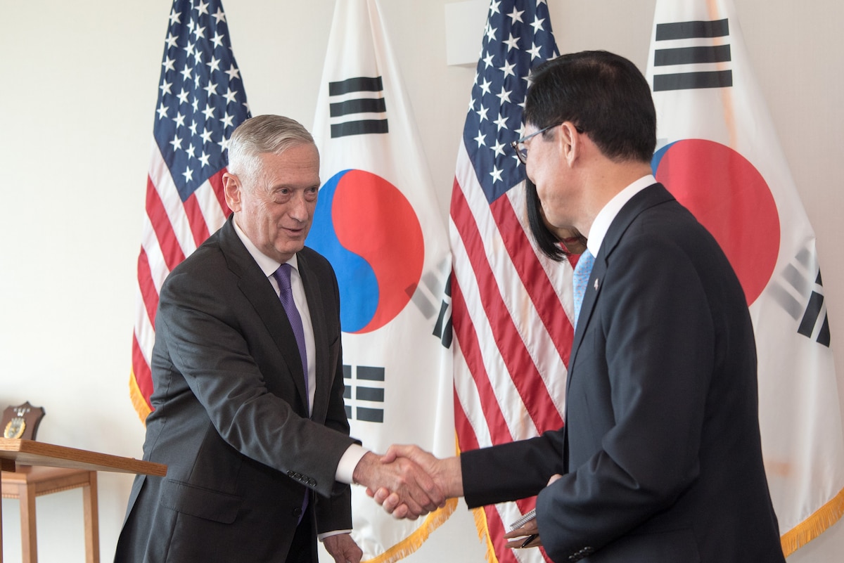 Defense Secretary James N. Mattis shake hands with his South Korean counterpart in front of a wall of flags.