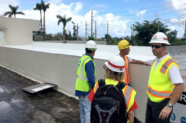 U.S. Army Corps of Engineers Critical Public Facilities Project Manager John Schreiner (right) inspects the contractor’s temporary roof repair progress at a medical facility in Puerto Rico.  The white roof in the back is a temporary rubber-like membrane applied to the existing flat roof to make it waterproof.