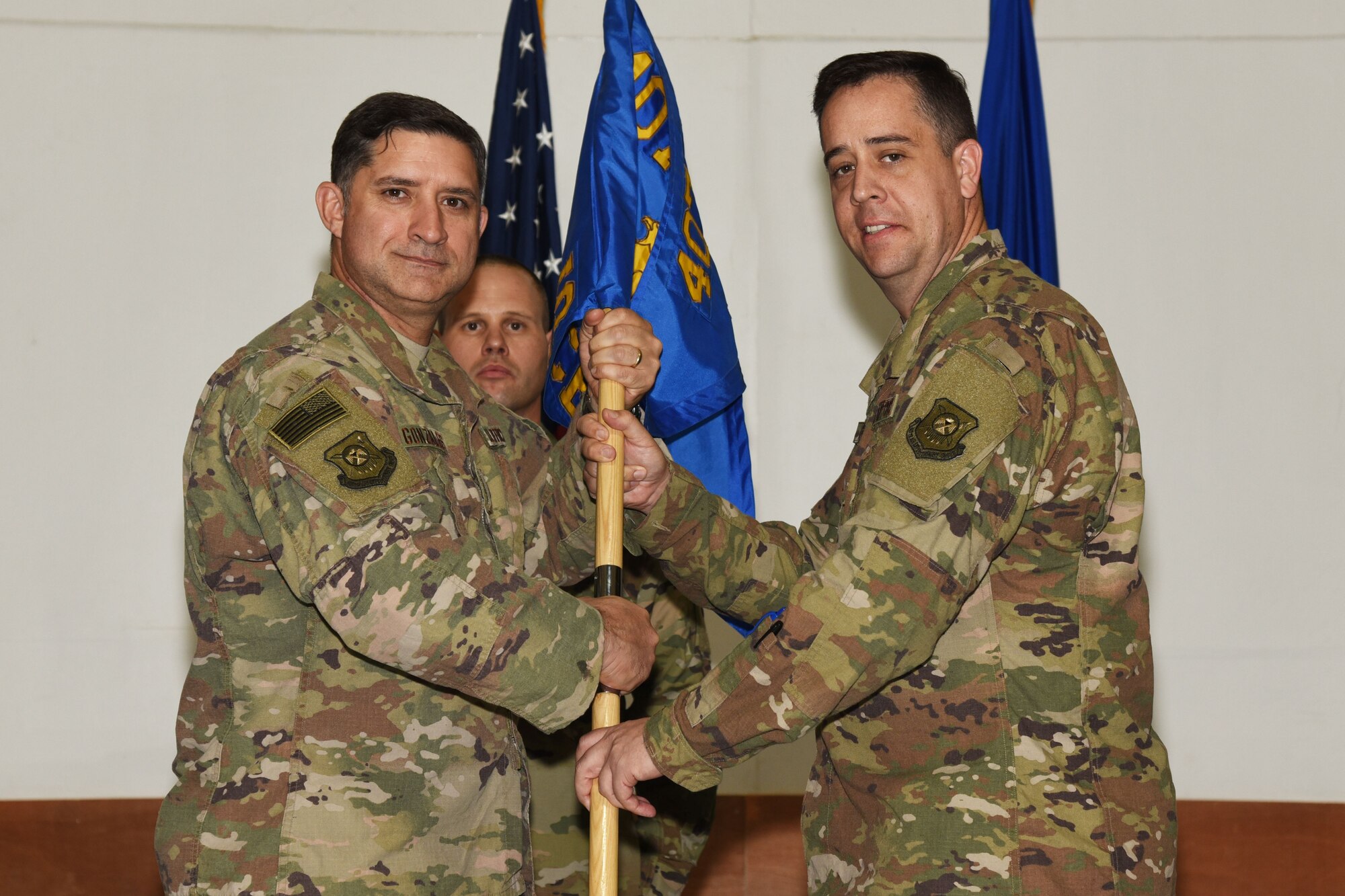 U.S. Air Force Col. John Gonzales, 407th Air Expeditionary Group Commander, passes a guidon to Lt. Col. Glenn Cameron, 407th Expeditionary Civil Engineer Squadron Commander, in Southwest Asia, January 25, 2018. The change of command ceremony is a time honored military tradition that signifies the orderly transfer of authority. (U.S. Air Force photo by Staff Sgt. Joshua Edwards/Released)