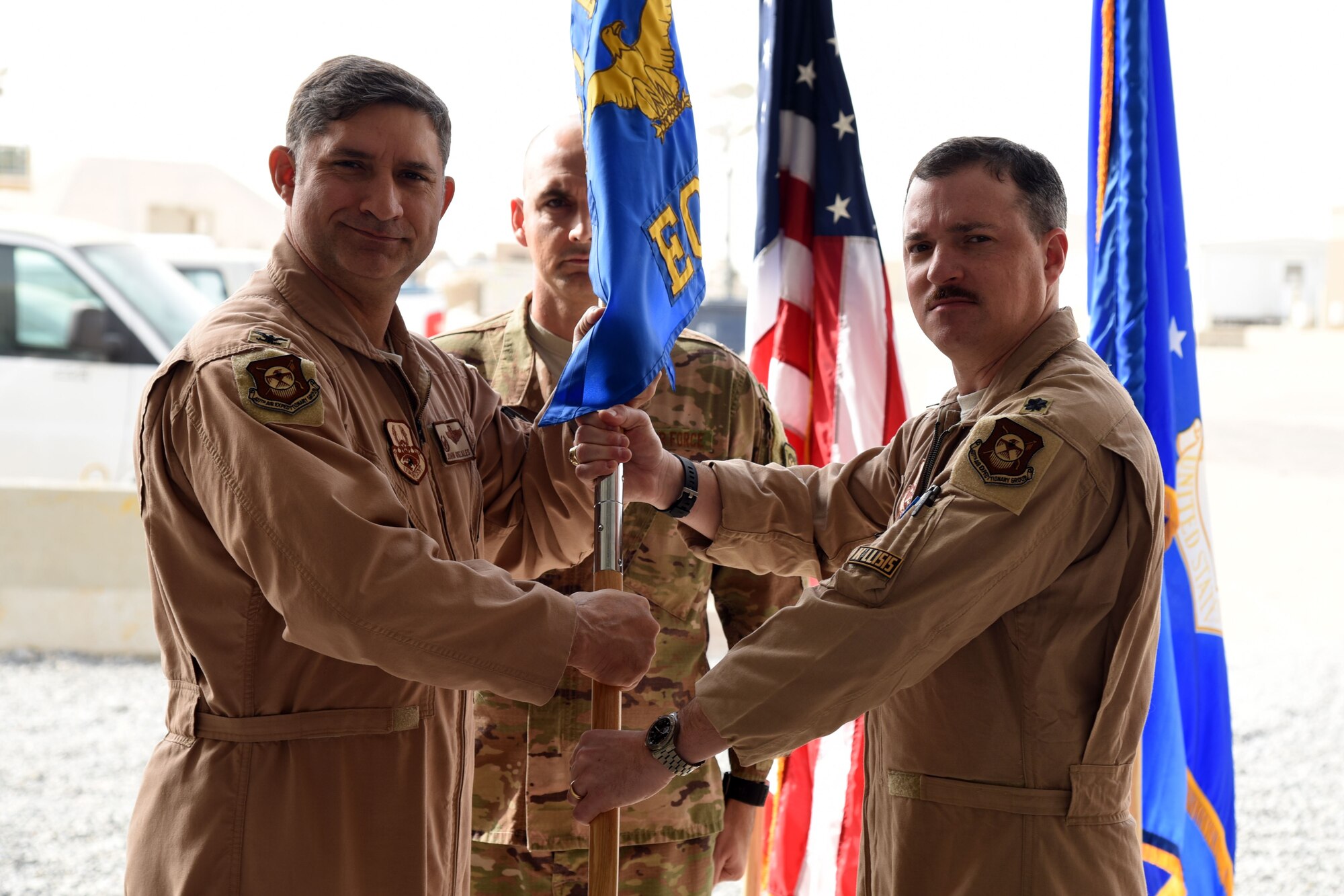 U.S. Air Force Col. John Gonzales, 407th Air Expeditionary Group Commander, passes a guideon to Lt. Col. Samuel Stitt, 407th Expeditionary Operations Support Squadron Commander in Southwest Asia, January 25, 2018. The change of command ceremony is a time honored military tradition that signifies the orderly transfer of authority. (U.S. Air Force photo by Staff Sgt. Joshua Edwards/Released)