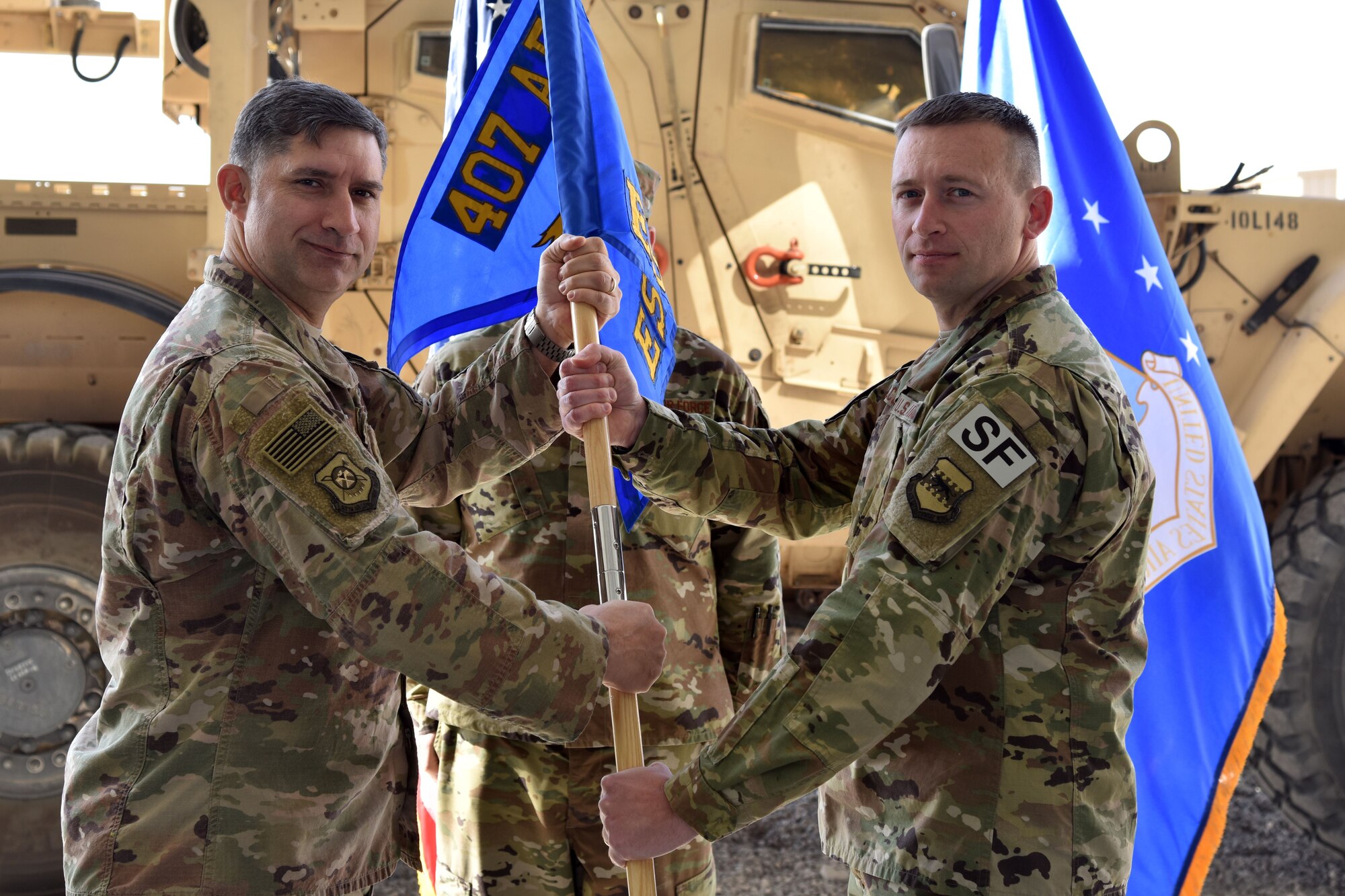 U.S. Air Force Col. John Gonzales, 407th Air Expeditionary Group Commander, passes a guidon to Maj. Aaron Gulczynski, 407th Expeditionary Security Forces Squadron Commander, in Southwest Asia, January 14, 2018. The change of command ceremony is a time honored military tradition that signifies the orderly transfer of authority. (U.S. Air Force photo by Staff Sgt. Joshua Edwards/Released)