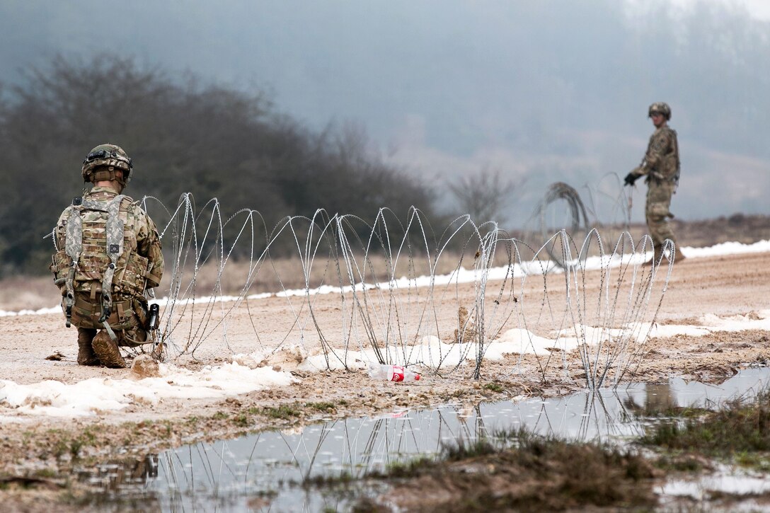 Army Sgt. Adam Caramanoff, left, and Pfc. Corey Allen set up a road block with concertina wire during the Allied Spirit VIII training exercise at Hohenfels Training Area, Germany.