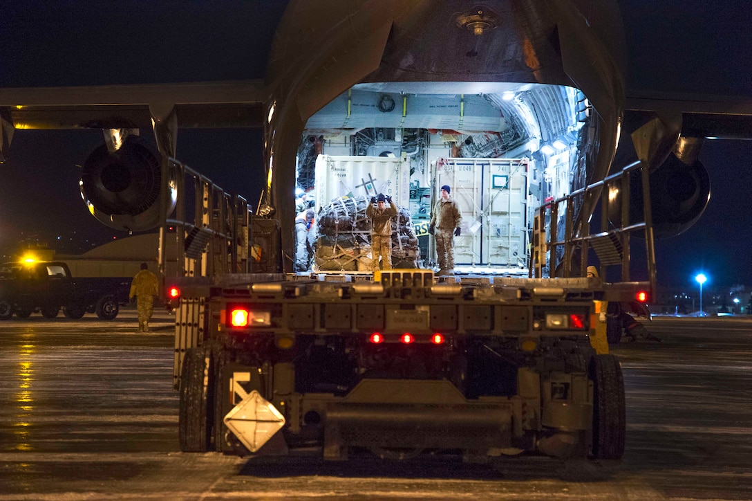 Soldiers prepare to unload cargo from a military aircraft.
