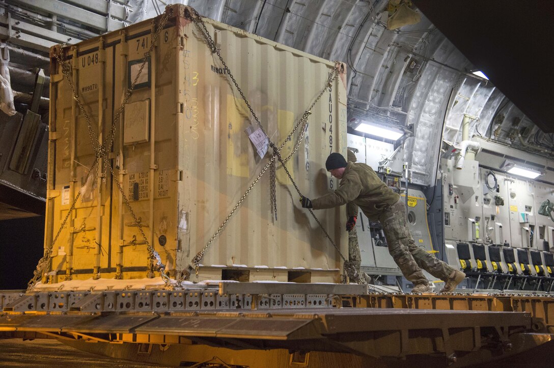 Soldiers unload a container from a military aircraft.