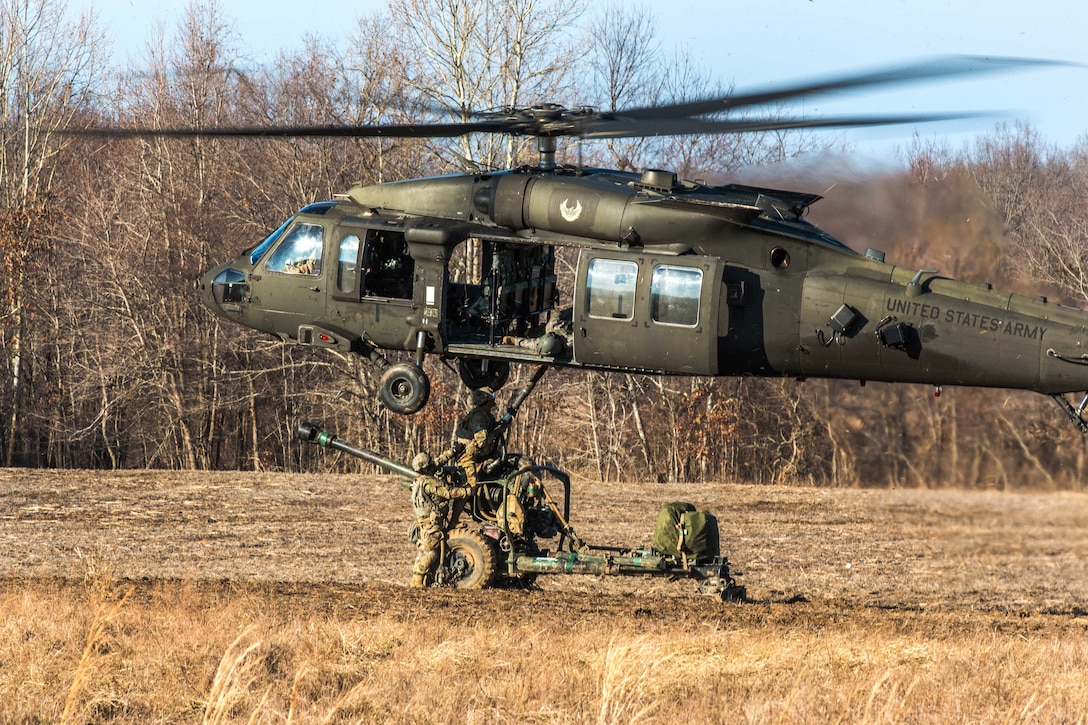 Soldiers slingload an M119A3 howitzer to a UH-60 Black Hawk helicopter during air assault operations at Fort Campbell, Kentucky.