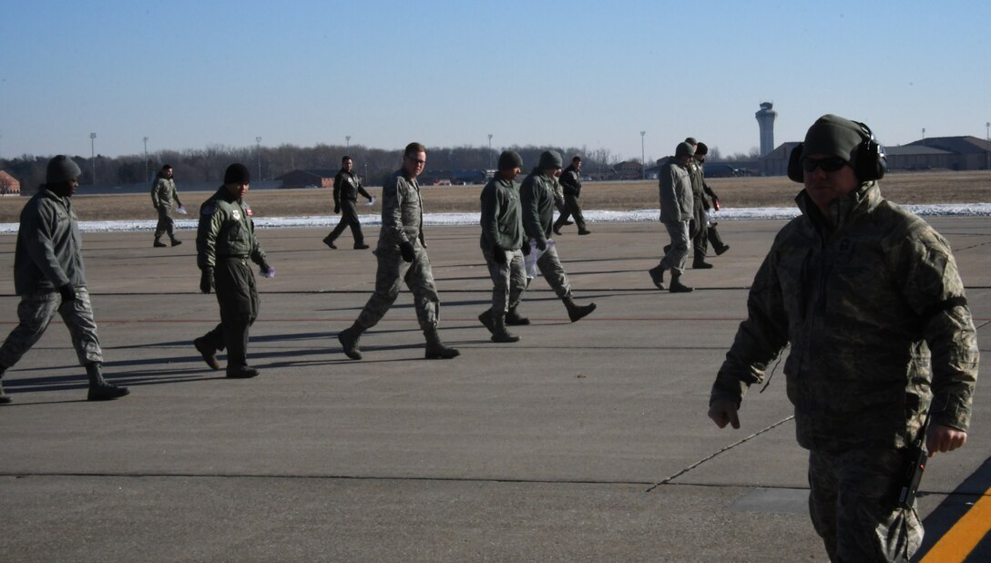 At right, Master Sgt. Bo Wilcox, C-40 plane maintainer from the 932nd Airlift Wing, 932nd Maintenance Squadron, moves toward the back of an aircraft while other Airmen walk the area looking for any small items on the ground that don't belong.  All successful 932nd Airlift Wing C-40C mission launches start days earlier with mission planning and aircraft preparation. Another area behind the scenes that's important is keeping the ramps and parking spots clean and ready to launch missions. Here, a team of maintenance and operations Airmen search the flight line for FOD (Foreign Object Damage) items Jan. 18, 2018, at Scott Air Force Base, Ill.. Time spent getting hands on the ramps during these "FOD walks" protects tires and engines of all incoming and outgoing aircraft. This is done by manually ensuring debris such as ice, trash, blowing leaves, and small rocks or twigs, some dropped by birds flying over, are removed from the flight line.  Sometimes a sweeper machine is also called in to assist such as after an ice storm. (U.S. Air Force photo by Lt. Col. Stan Paregien)