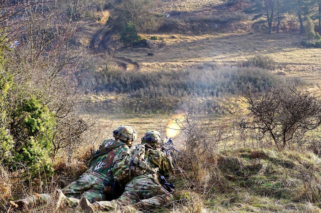 Two soldiers firing a machine gun from an elevated location.
