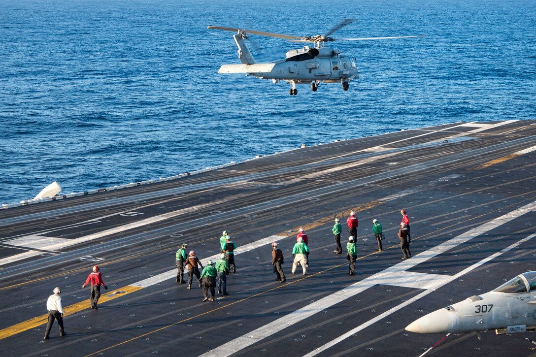 A military helicopter takes off from the flight deck of the aircraft carrier USS Carl Vinson.