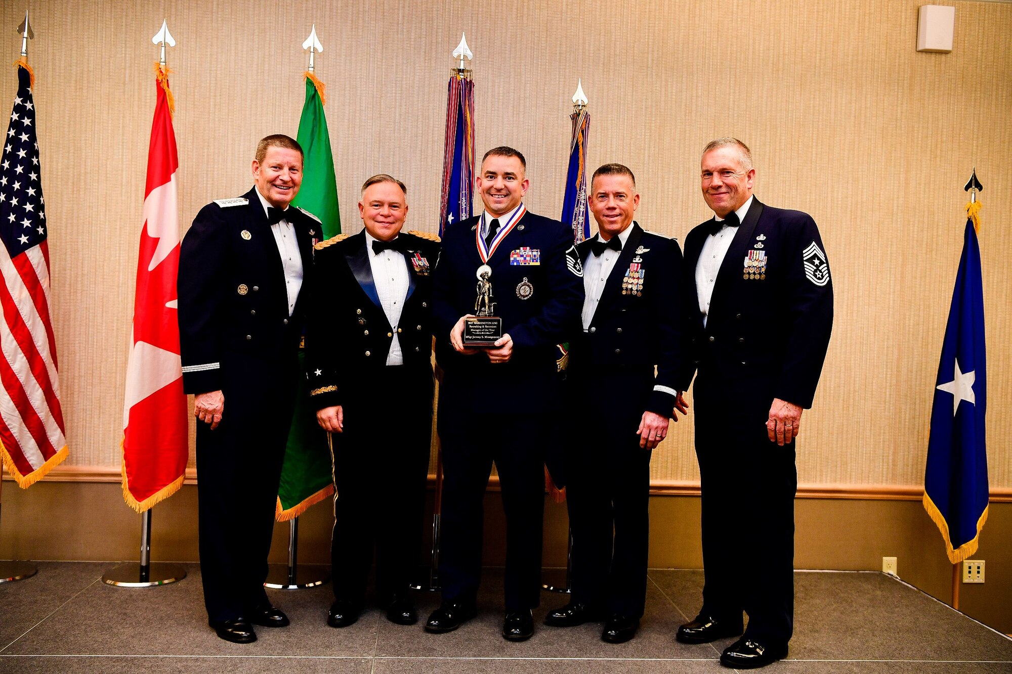 Master Sgt. Jeremy Montgomery, a recruiter with the Washington Air National Guard, is presented with the Recruiting and Retention Manager of the Year trophy at the Washington Air National Guard’s 9th Annual Awards Banquet held at the American Lake Conference Center on Joint Base Lewis-McChord, Washington, Jan. 27, 2018.  Montgomery was awarded the trophy for his outstanding contributions to the Washington Air National Guard over the last year.  Pictured from left to right are: Gen. Robin Rand, Air Force Global Strike Command and Air Forces Strategic-Air, U.S. Strategic Command commander; Maj. Gen. Bret Daugherty, Adjutant General of the Washington National Guard, Montgomery, Montgomery, Brig. Gen. Jeremy Horn, commander of the Washington Air National Guard, and Chief Master Sgt. Max Tidwell, Washington Air National Guard command chief. (U.S. Air National Guard photo by Tech. Sgt. Timothy Chacon)