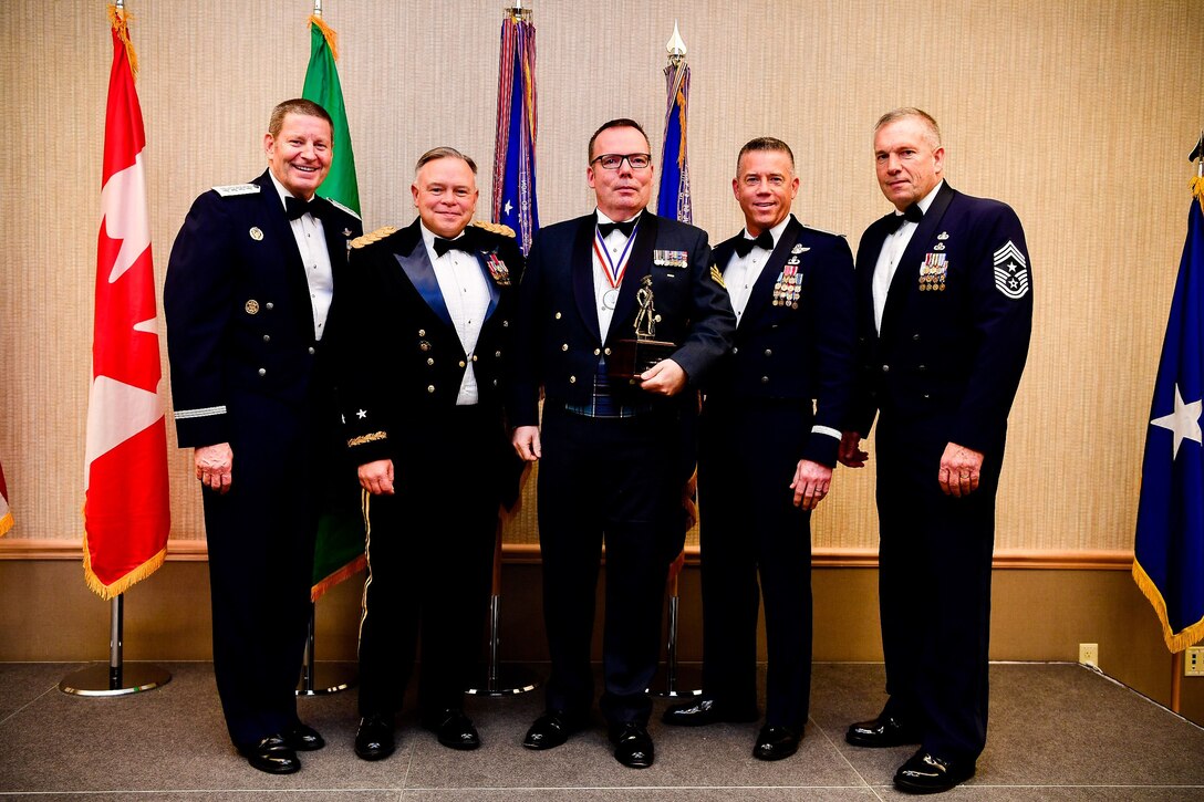 Royal Canadian Air Force Sgt. Yves Truchon, a command and control battle manager with the 225th Air Defense Squadron and Canadian Detachment, Western Air Defense Sector, is presented with the Honor Guard Manager of the Year trophy at the Washington Air National Guard’s 9th Annual Awards Banquet held at the American Lake Conference Center on Joint Base Lewis-McChord, Washington, Jan 27, 2018. Truchon was awarded the trophy for his outstanding contributions to the Washington Air National Guard over the last year.  Pictured from left to right are: Gen. Robin Rand, Air Force Global Strike Command and Air Forces Strategic-Air, U.S. Strategic Command commander, Maj. Gen. Bret Daugherty, Adjutant General of the Washington National Guard, Truchon, Brig. Gen. Jeremy Horn, commander of the Washington Air National Guard, and Chief Master Sgt. Max Tidwell, Washington Air National Guard command chief. (U.S. Air National Guard photo by Tech. Sgt. Timothy Chacon)