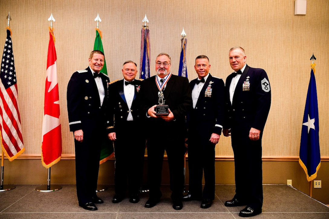 Randy Toulou, a unit readiness training coordinator with the 141st Security Forces Squadron, 141st Air Refueling Wing, is presented with the Civilian of the Year trophy at the Washington Air National Guard’s 9th Annual Awards Banquet held at the American Lake Conference Center on Joint Base Lewis-McChord, Washington, Jan. 27, 2018. Toulou was awarded the trophy for his outstanding contributions to the Washington Air National Guard over the last year.  Pictured from left to right are: Gen. Robin Rand, Air Force Global Strike Command and Air Forces Strategic-Air, U.S. Strategic Command commander; Maj. Gen. Bret Daugherty, Adjutant General of the Washington National Guard, Toulou, Brig. Gen. Jeremy Horn, commander of the Washington Air National Guard, and Chief Master Sgt. Max Tidwell, Washington Air National Guard command chief. (U.S. Air National Guard photo by Tech. Sgt. Timothy Chacon)