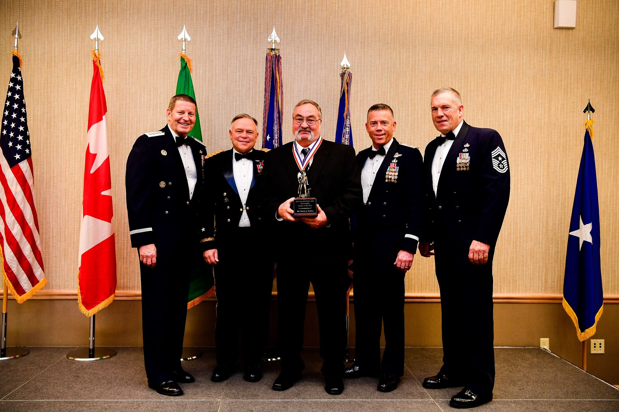 Randy Toulou, a unit readiness training coordinator with the 141st Security Forces Squadron, 141st Air Refueling Wing, is presented with the Civilian of the Year trophy at the Washington Air National Guard’s 9th Annual Awards Banquet held at the American Lake Conference Center on Joint Base Lewis-McChord, Washington, Jan. 27, 2018. Toulou was awarded the trophy for his outstanding contributions to the Washington Air National Guard over the last year.  Pictured from left to right are: Gen. Robin Rand, Air Force Global Strike Command and Air Forces Strategic-Air, U.S. Strategic Command commander; Maj. Gen. Bret Daugherty, Adjutant General of the Washington National Guard, Toulou, Brig. Gen. Jeremy Horn, commander of the Washington Air National Guard, and Chief Master Sgt. Max Tidwell, Washington Air National Guard command chief. (U.S. Air National Guard photo by Tech. Sgt. Timothy Chacon)