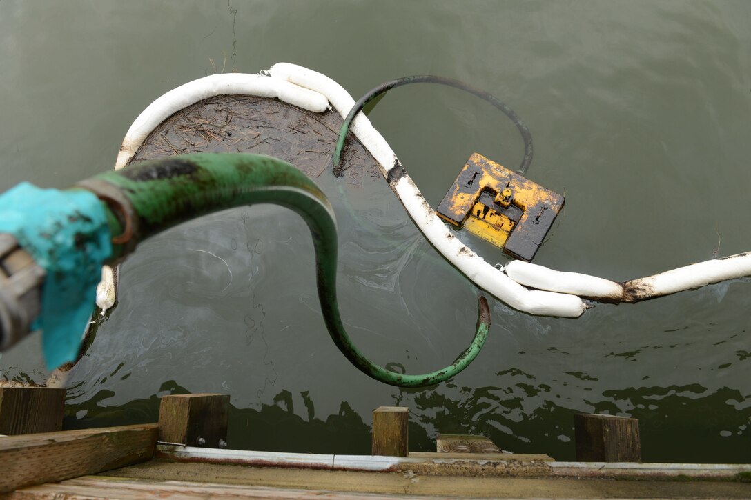 A long hose drapes off the side of a bridge into the river.