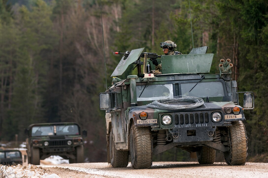 A soldier mans a machine gun on a moving Humvee.
