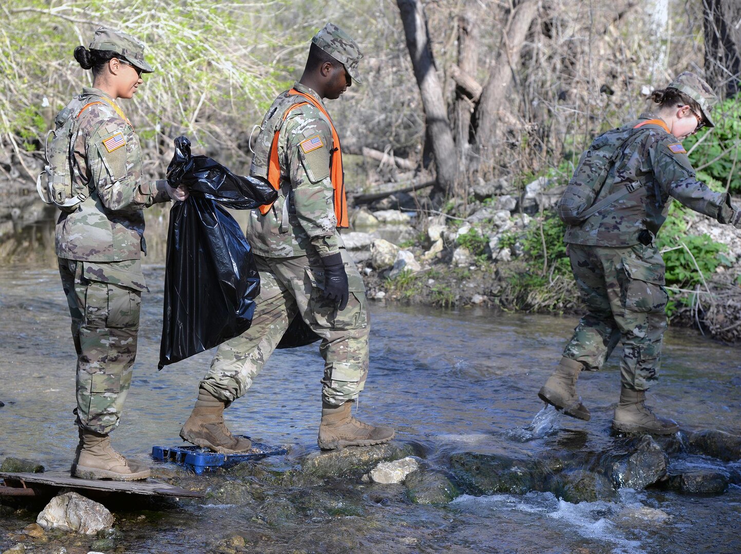 Why did the Soldiers cross the stream? To get to the other side and pick up more trash during the 2017 Basura Bash at Joint Base San Antonio-Fort Sam Houston.