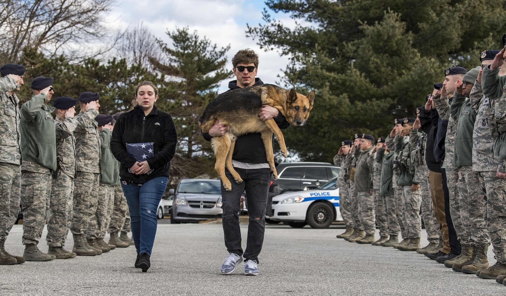 Members of the 436th Security Forces Squadron render a final salute to retired Military Working Dog Rico as his former handler and current owner, retired Tech. Sgt. Jason Spangenberg, carries him to the Veterinary Treatment Facility Jan. 24, 2018, on Dover Air Force Base, Del. Mya Spangenberg accompanied her father as they walked through the cordon. (U.S. Air Force photo by Roland Balik)