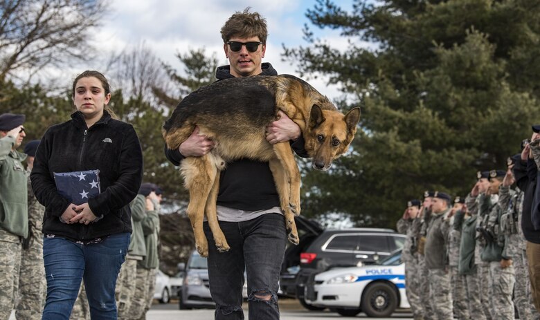 Members of the 436th Security Forces Squadron render a final salute to retired Military Working Dog Rico as his former handler, retired Tech. Sgt. Jason Spangenberg, carries him to the Veterinary Treatment Facility Jan. 24, 2018, on Dover Air Force Base, Del. Mya Spangenberg carried a U.S. flag as she accompanied her father. (U.S. Air Force photo by Roland Balik)