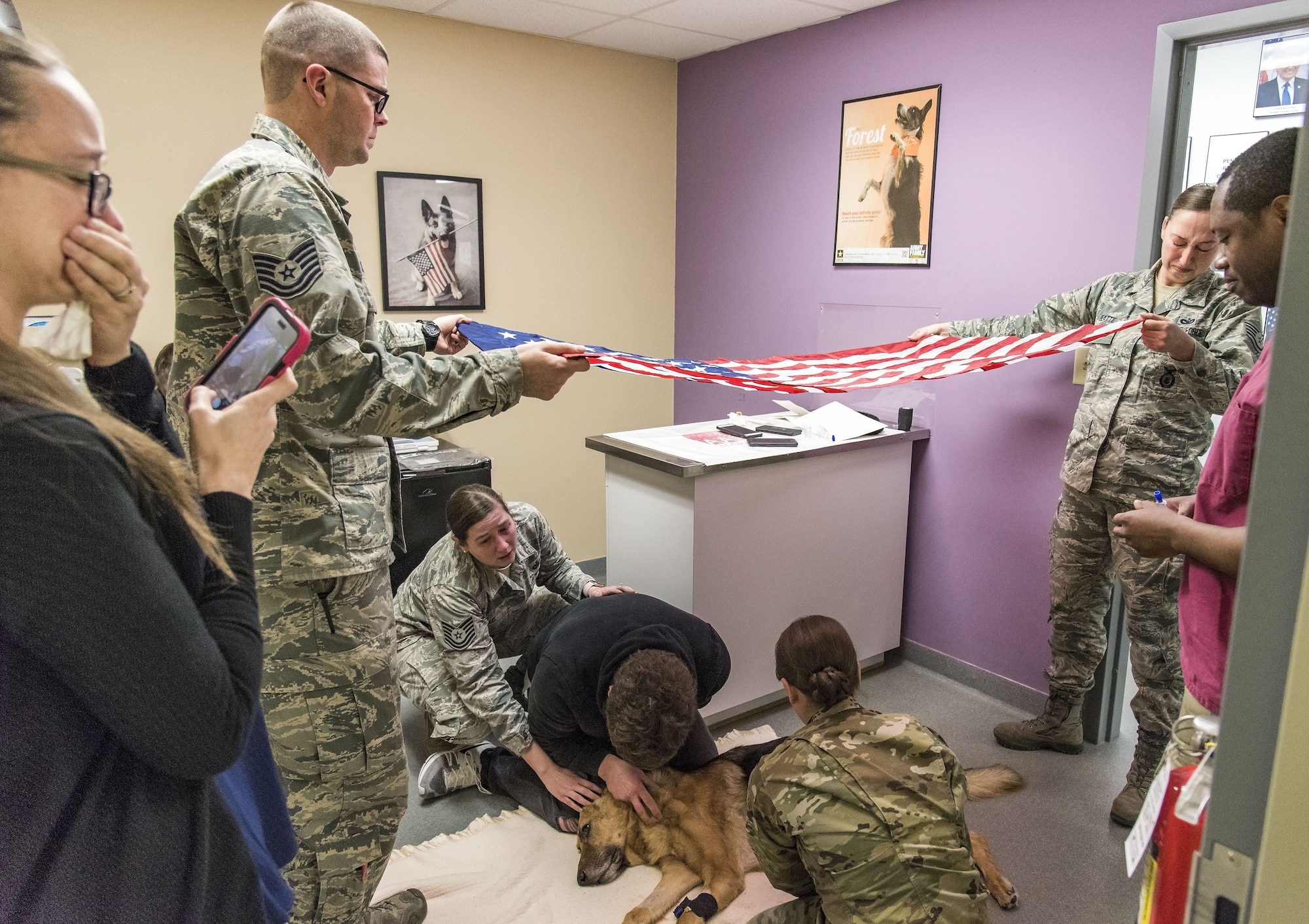 Tech. Sgt. Matthew Salter, 436th Security Forces Squadron military working dog kennel master, and Staff Sgt. Ashley Beattie, 436th SFS unit deployment manager, hold the U.S. flag over retired Military Working Dog Rico Jan. 24, 2018, at the Veterinary Treatment Facility on Dover Air Force Base, Del. MWD Rico was humanely euthanized by a U.S. Army veterinarian due to his declining health caused by Canine Degenerative Myelopathy. (U.S. Air Force photo by Roland Balik)