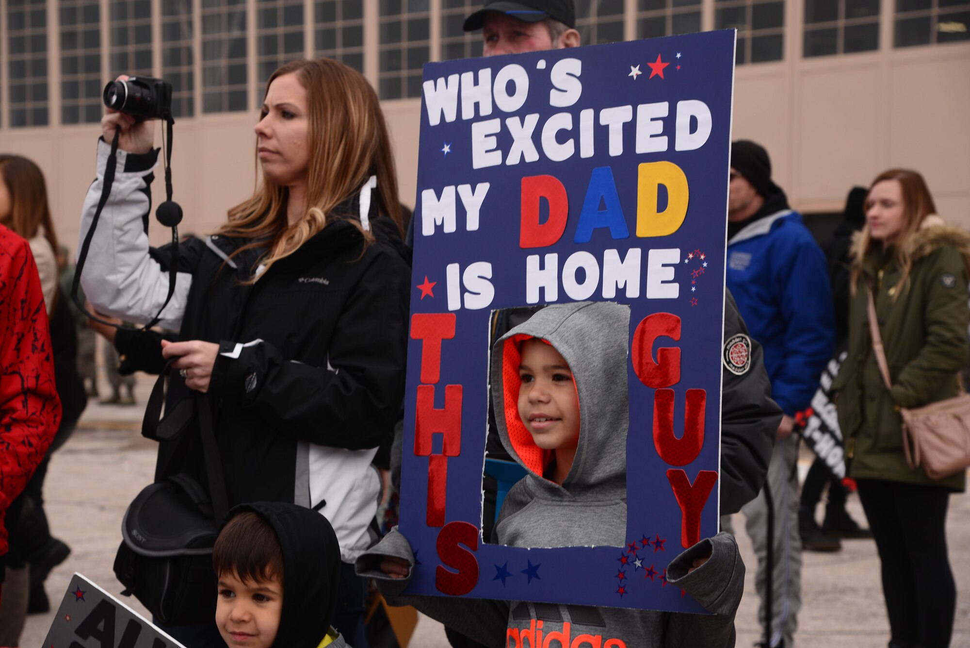 Aziah Dominguez holds a sign to show his excitement for the return of his father at the Pride Hangar at Ellsworth Air Force Base, S.D., Jan. 29, 2018. B-1 Bombers from the 37th Bomb Squadron and Airmen from the 37th Aircraft Maintenance Unit were deployed to Andersen AFB, Guam, to take part in the Continuous Bomber Presence mission. (U.S. Air Force photo by Airman 1st Class Donald Knechtel)