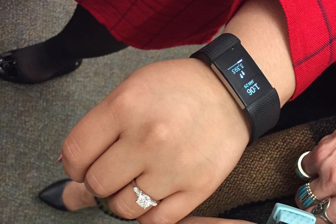 A woman shows a fitness tracker on her wrist.