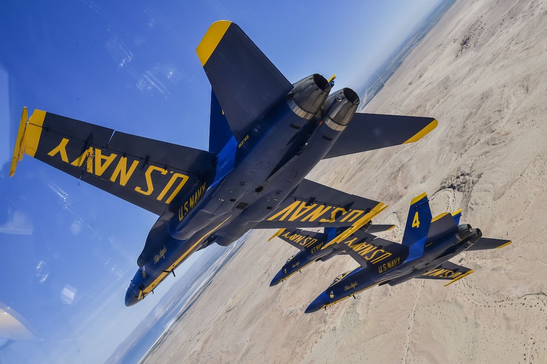 Pilots assigned to the Navy's demonstration squadron fly at an angle over land.