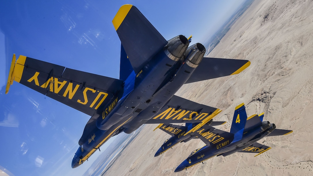 Pilots assigned to the Navy's demonstration squadron fly at an angle over land.