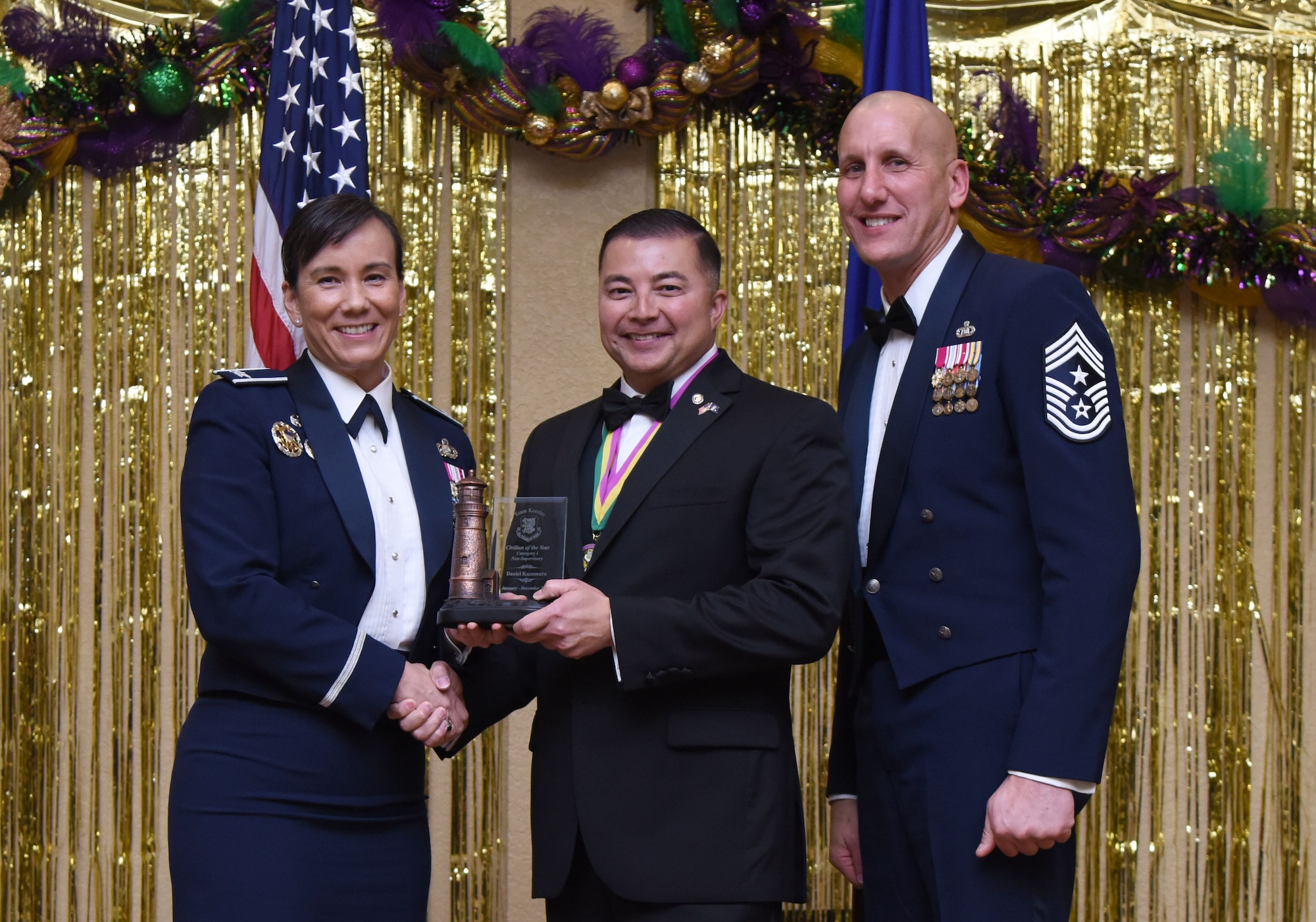 Col. Debra Lovette, 81st Training Wing commander, and Chief Master Sgt. Kenneth Carter, 81st TRW command chief, present Daniel Kazumura, 81st Training Wing legal assistant, with the Civilian Non-Supervisory Category I Annual Award during the 2017 Keesler Annual Awards Ceremony at the Bay Breeze Event Center Jan. 25, 2018, on Keesler Air Force Base, Mississippi. During the ceremony base leadership recognized outstanding Airmen and civilians from across the installation for their accomplishments throughout 2017. (U.S. Air Force photo by Kemberly Groue)