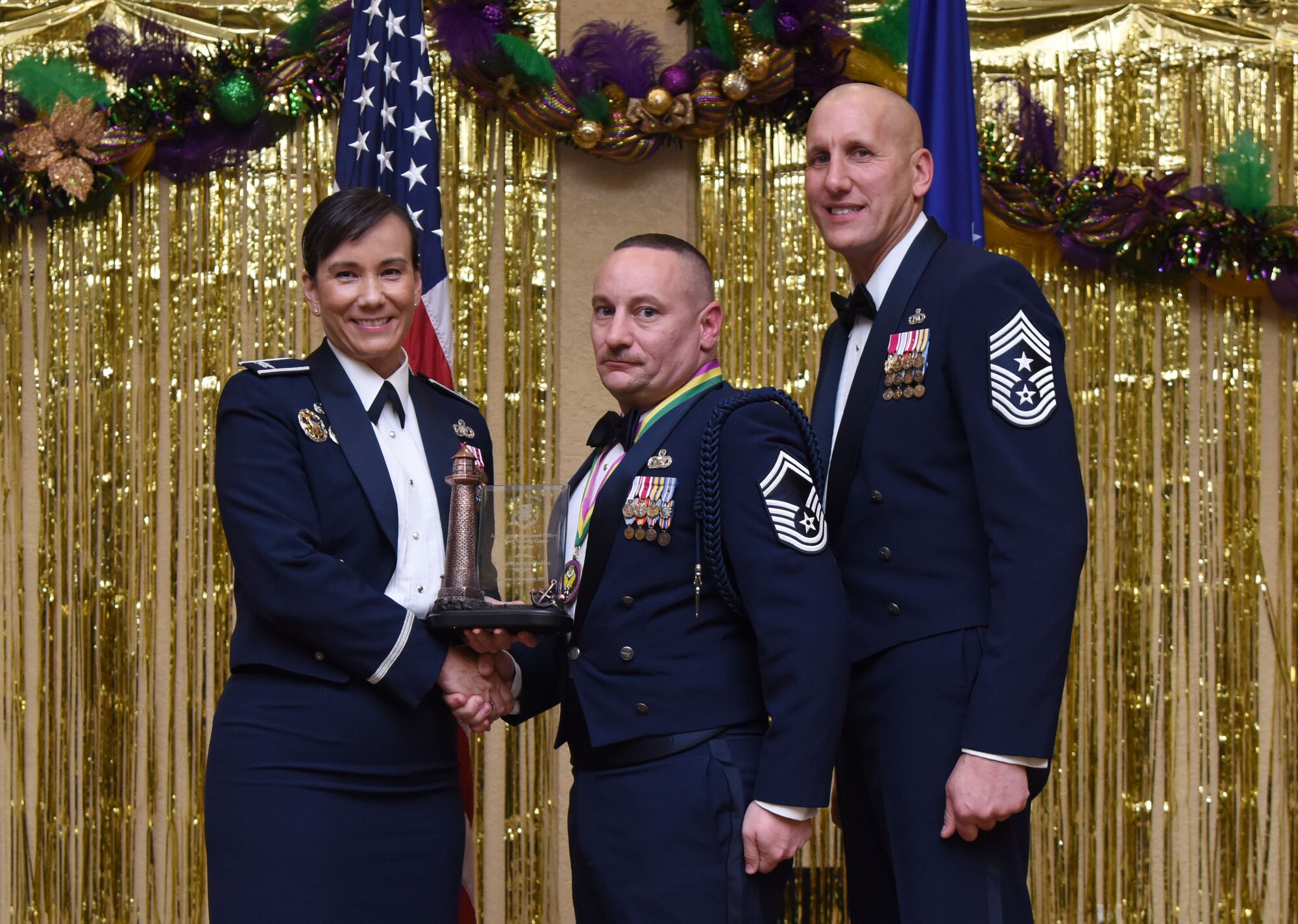 Col. Debra Lovette, 81st Training Wing commander, and Chief Master Sgt. Kenneth Carter, 81st TRW command chief, present Senior Master Sgt. Andrew Bodine, 81st Training Group superintendent of military training, with the Senior NCO Military Training Leader of the Year Annual Award during the 2017 Keesler Annual Awards Ceremony at the Bay Breeze Event Center Jan. 25, 2018, on Keesler Air Force Base, Mississippi. During the ceremony base leadership recognized outstanding Airmen and civilians from across the installation for their accomplishments throughout 2017. (U.S. Air Force photo by Kemberly Groue)