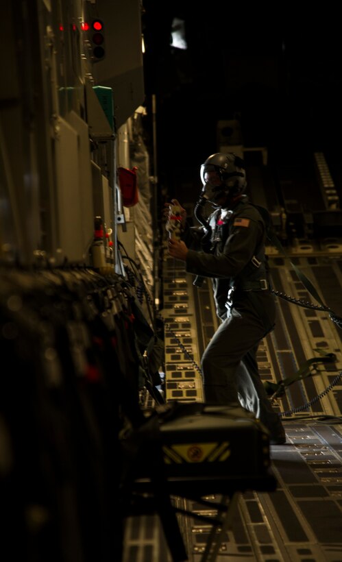 Tech. Sgt. Justin Davenport, 535th Airlift Squadron loadmaster, tosses a tracker out of a C-17 Globemaster III during an airdrop mission over Big Island, Hawaii, Jan. 25, 2018. Airdrop missions are part of the routine training for aircrew and logistics personnel. (U.S. Air Force photo by Tech. Sgt. Heather Redman)