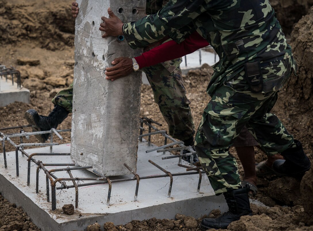Royal Thai Army soldiers and Marines place the main pillar of a multifunctional building onto its concrete pad during a pillar-raising ceremony in support of Exercise Cobra Gold 2018 at Ban Pan Mo School in Chanthaburi Province, Kingdom of Thailand, Jan. 24, 2018. The ceremony marked the official start of engineering civic assistance projects for the exercise. Cobra Gold is in its 37th iteration, and humanitarian civic assistance projects conducted during the exercise support the needs and humanitarian interests of the Thai people. (U.S. Marine Corps photo by Sgt. Matthew J. Bragg)
