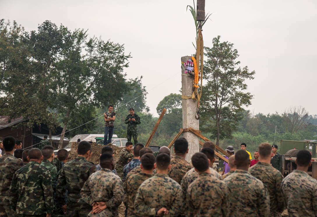 Royal Thai Armed Forces, alongside U.S. Marines and Japan Ground Self-Defense Force members, observe the main pillar of a multifunctional building during a pillar-raising ceremony in support of Cobra Gold 2018 at Ban Pan Mo School in Chanthaburi, Kingdom of Thailand, Jan. 24, 2018. The ceremony marked the official start of engineering civic assistance projects for the exercise. (U.S. Marine Corps photo by Sgt. Matthew J. Bragg)