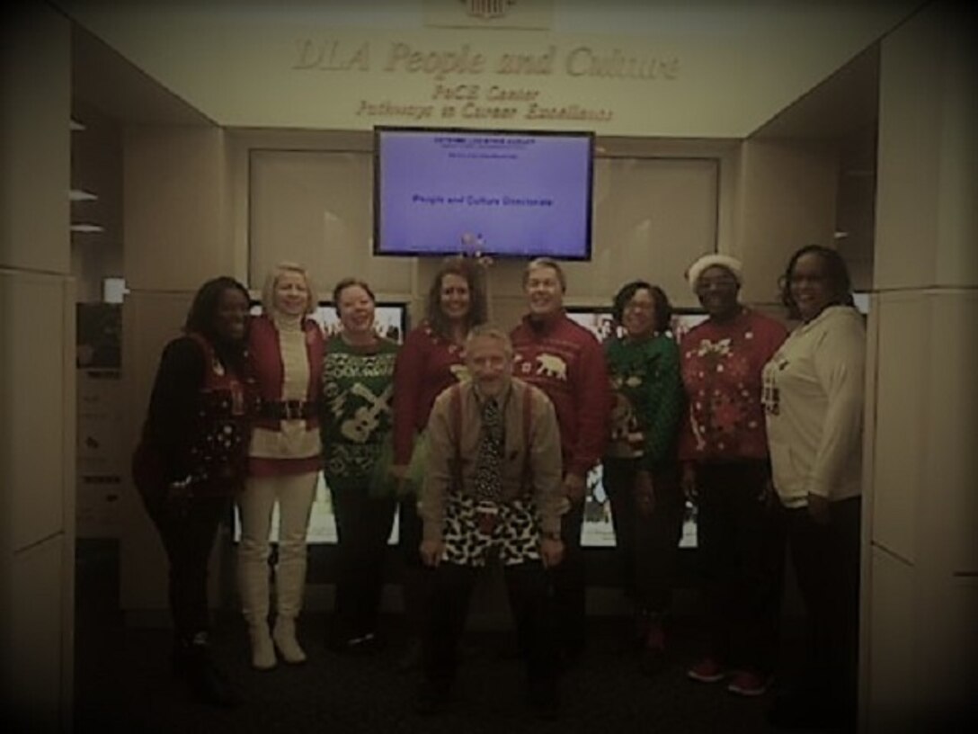 Participants in the Ugly Sweater Contest from People and Culture, pose for a group picture before heading off to Command.